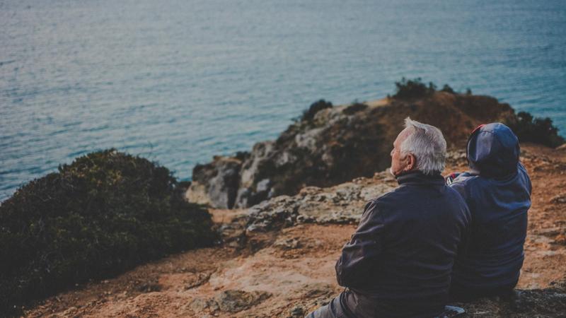 Ett äldre par som sitter på en klippa och tittar ut över havet